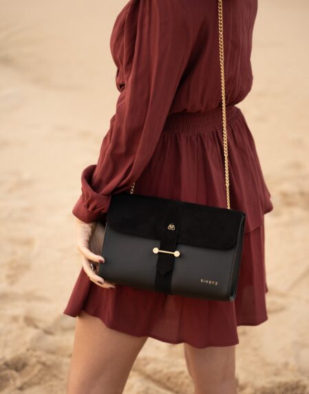 woman in red long sleeve shirt and black skirt carrying black leather handbag