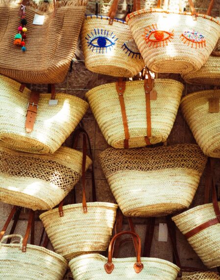 Various straw bags are displayed for sale.