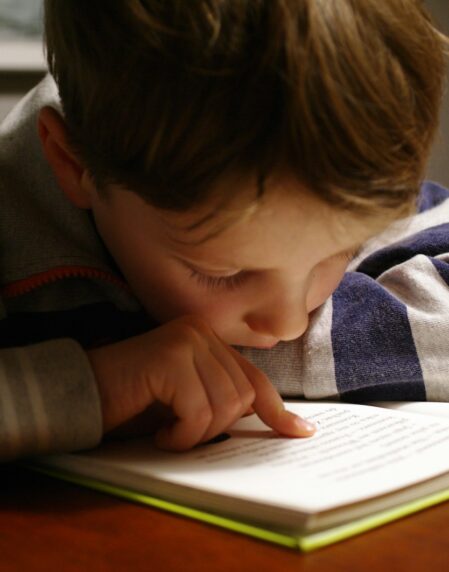 boy in gray and red hoodie reading book