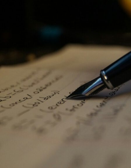 a person writing on a piece of paper with a pen